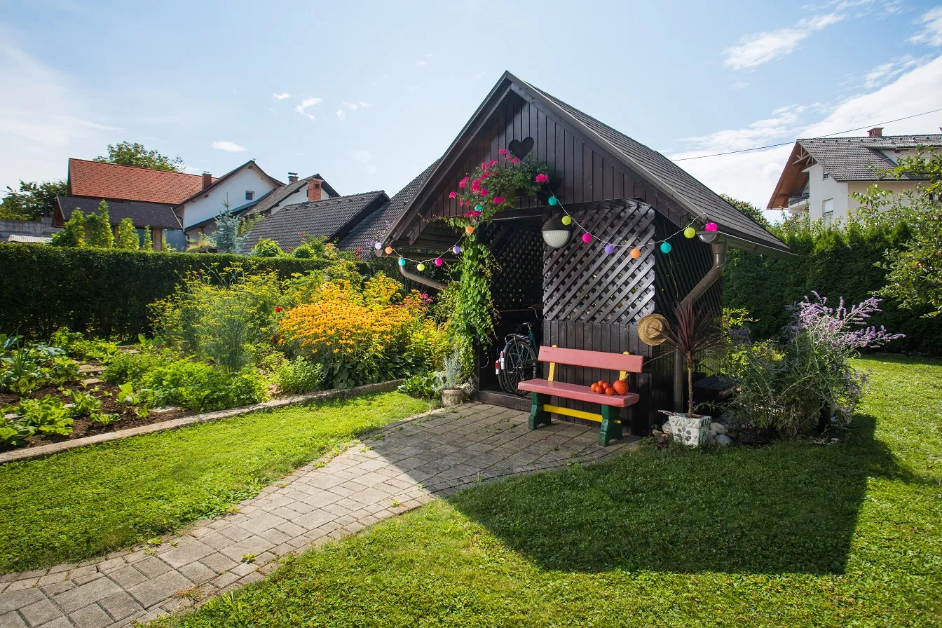 Vrtna uta s klopco in rožami sredi vrta